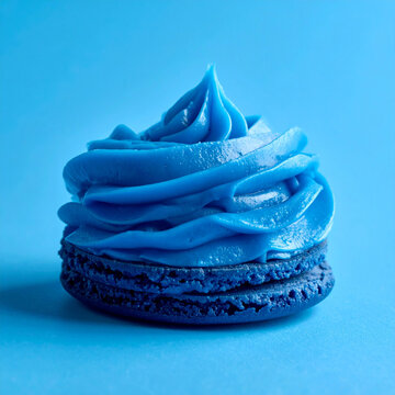 Single gourmet blue macaron with cream swirl on minimalist blue background