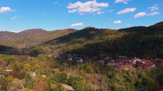 Private houses overlooking rolling hills near Asheville during peak autumn season. Colorful forests surround peaceful mountain community in North Carolina.