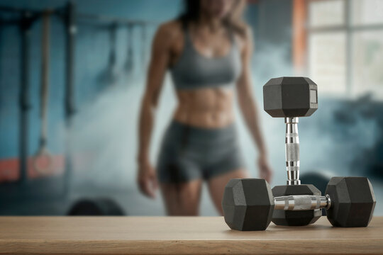 Dumbbells on wooden bench with blurred gym interior &ndash; fitness and strength training concept. Ideal for sports advertising, fitness campaigns, gym promotions, health and wellness concepts and product.