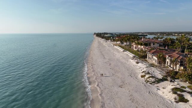 Still shot of a couple walking on a nearly empty sandy beach at Casey Key, a barrier island, in Sarasota County, Florida. 