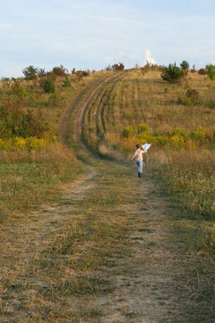 Child running with a kite along a rural path