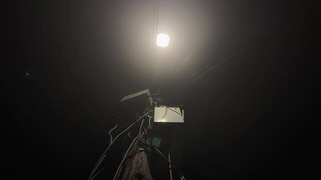 Mess of electric wire cables on powerline post at night