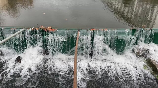 A river with a green wall plastic artificial dam and water flowing