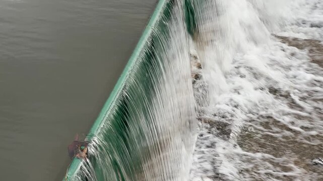 A river with a green wall plastic artificial dam and water flowing