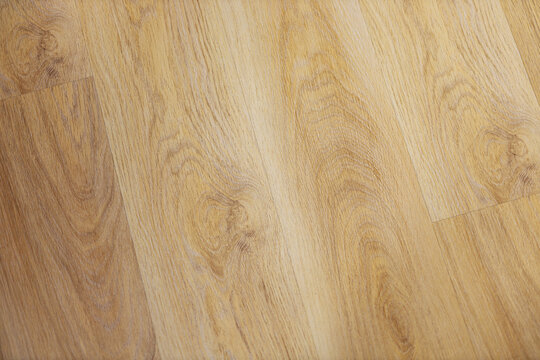 Closeup view of warm golden wooden plank surface with detailed natural grain, visible knots, fine pores, and subtle linear texture across panel for background