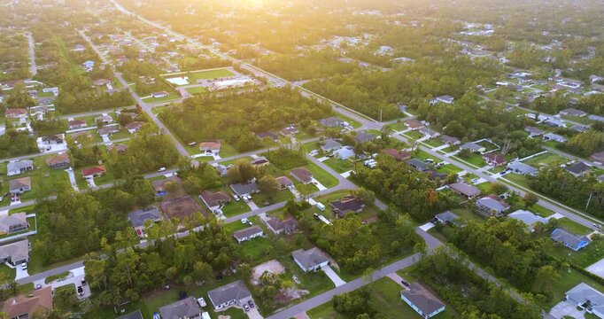 Suburban neighborhood at sunset with spacious homes and tropical vegetation, capturing scenic town views, warm climate and desirable residential destination in Florida.