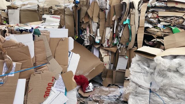 A pile of cardboard boxes and trash. Scene is chaotic and messy. The boxes are piled high, and the trash is scattered around, creating a disorganized and cluttered scene