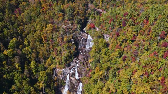 Waterfall flows through vibrant fall forest in remote gorge. Whitewater Falls in November, nestled in the wooded mountains of North Carolina, USA.
