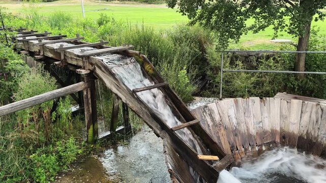 Water flow trough with a vintage wooden swirl washing machine and a wooden handle
