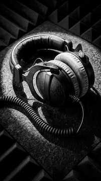 Professional black and white studio headphones resting on soundproofing foam in recording studio