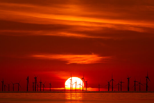 Vibrant red sunset behind offshore wind turbines at Talacre Beach in Flintshire North Wales
