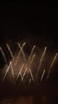 Golden firework trails crossing the night sky, vertical video