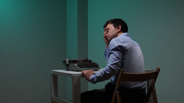 Man feeling stressed and frustrated, sitting at a desk with an old typewriter, experiencing writer's block and headache while trying to work on a difficult project