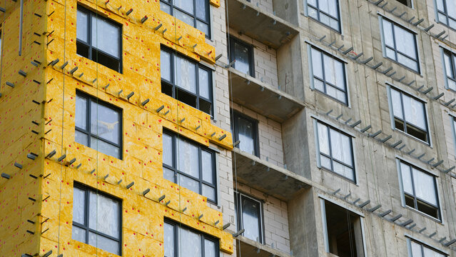 Close view of exterior insulation installation on a modern apartment building, showing construction materials, facade systems and energy efficient building solutions