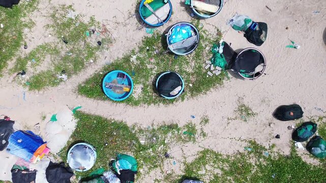 Top down aerial drone perspective capturing geometric pattern of blue round traditional Vietnamese coracle fishing basket boats parked on sandy beach shore in Mui Ne bay near Phan Thiet.