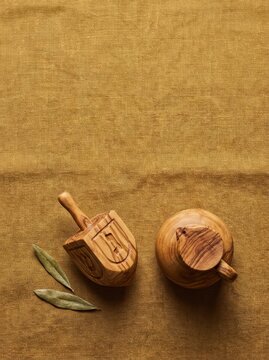 Olive wood objects on linen fabric with bay leaves, featuring a decorative bowl and a small container in a warm, earthy color palette