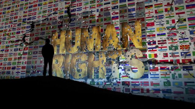Silhouette Facing Giant Human Rights Message Against a World Flags Background