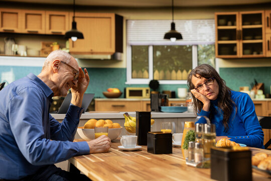 Distant and unamused wife feels drained as her elderly husband keeps speaking during a morning meal, with homemade breakfast framing a strained retirement relationship and her fed-up mood.