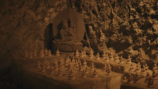 Rows of miniature stone statues surround a carved relief deity inside the atmospheric Benten-kutsu cave shrine at Hasedera Temple in Kamakura, Japan, evoking centuries of devotional tradition.