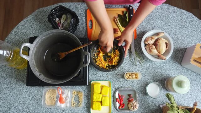 Top view of crushing fresh ingredients with mortar and pestle for chicken coconut curry