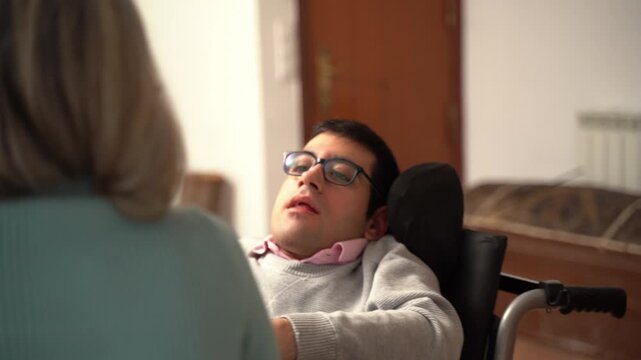 Disabled man in a wheelchair receiving care from his mother at home