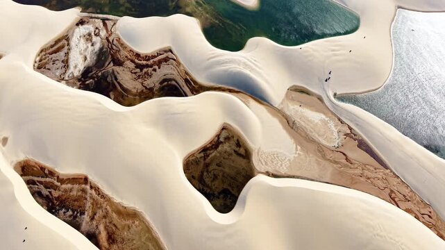 Overhead aerial drone view of rows of white dunes and clear lagoons spreading across the desert, Lencois Maranhenses, Brazil