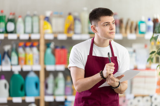 Male seller makes notes on paper - keeps track of the receipt and expenditure of goods in a supermarket