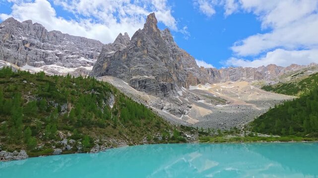 Timelapse of turquoise Lake Sorapis surrounded by dramatic rocky peaks in the Italian Dolomites, with fast-moving clouds and light reflections