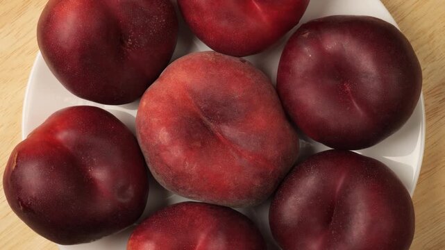 Ripe nectarines and flat peach rotating on a plate
