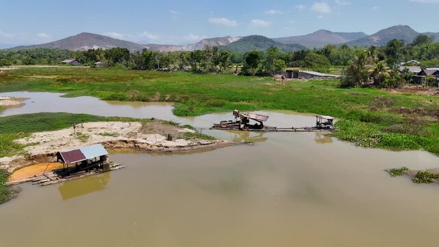 Small mining boats operating on the muddy river surface surrounded by green landscape in Indonesia