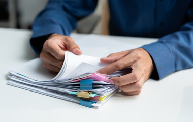 Close-up of professional businessman hands searching financial document files with colorful sticky...