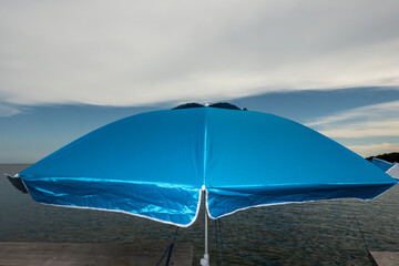 Point Lookout, Maryland A blue sun umbrella or parasol sits on a pier in the Chesapeake Bay. © Alexander