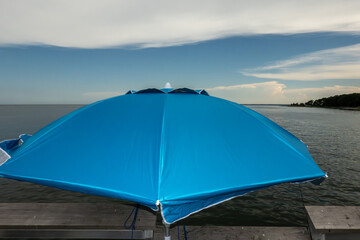 Point Lookout, Maryland A blue sun umbrella or parasol sits on a pier in the Chesapeake Bay. © Alexander