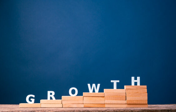 Business growth and step-by-step progress with GROWTH letters on rising wooden stairs