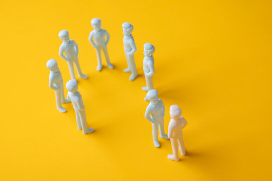 Social exclusion and outsider concept with one person blocked from joining a group