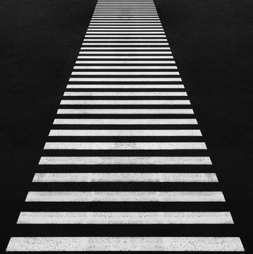 Abstract view of a pedestrian crossing with black and white stripes on asphalt pedestrian crossing on the street Empty pedestrian crosswalk with bright white stripes on dark asphalt bordered by  lines