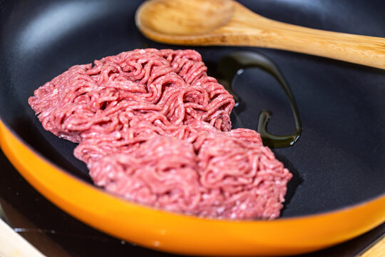 Raw Ground Beef Frying in a Pan with Cooking Oil and Wooden Spoon for Fresh Homemade High Protein Low Carb Meal