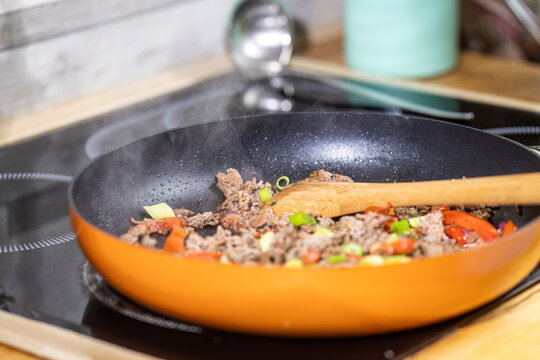 Raw Ground Beef Frying in a Pan with Cooking Oil and Wooden Spoon for Fresh Homemade High Protein Low Carb Meal