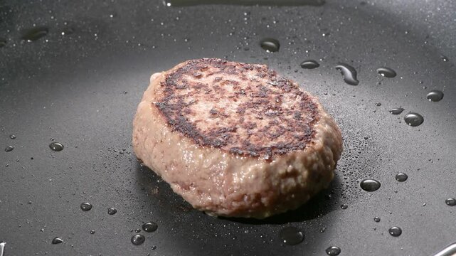 Grilled hamburger steak patty with seared crust cooking on a black griddle, camera zooms in and pans across the surface