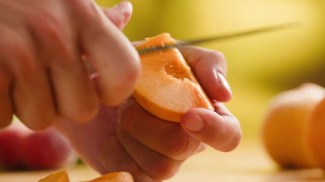 Chef cutting peach, apricot or nectarine with knife, preparing fruit salad for breakfast, homemade jam and juice