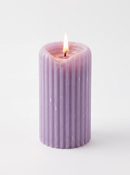 Minimal purple ribbed pillar candle with realistic burning flame isolated on white background. Elegant decorative wax candle for home decor, spa, relaxation, holiday, and branding projects.