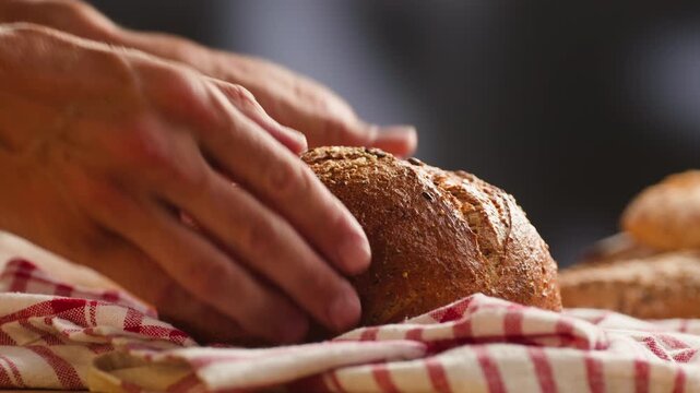 Bread loaf Spanish round bread with seeds, held in hands on checkered cloth, close-up macro shot