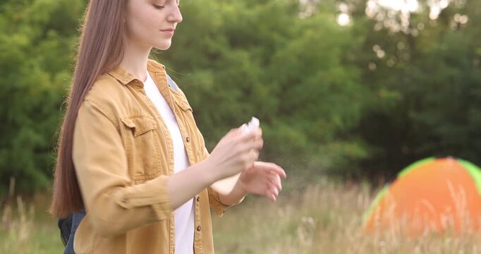 Woman spraying insect repellent onto her arm outdoors, closeup