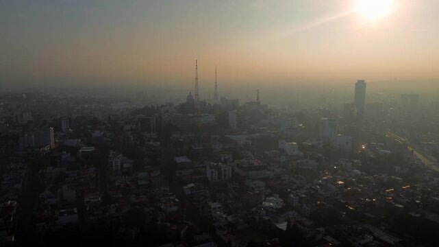 Puebla cityscape at sunset with mist surrounding La Paz neighborhood and its distinctive white dome church above the expanding urban landscape