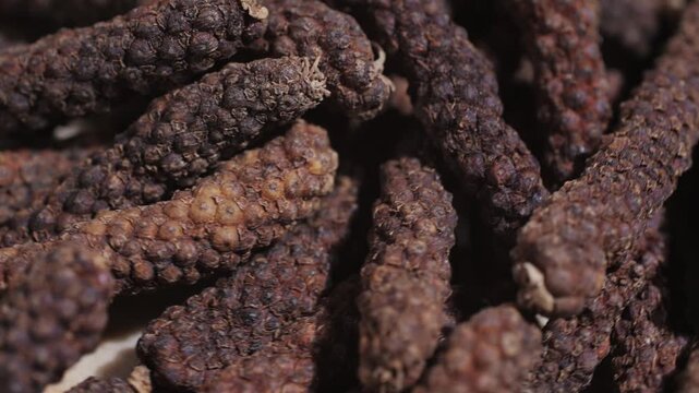 Indonesian long black peppercorns, close up of spices, dry hot pepper. 