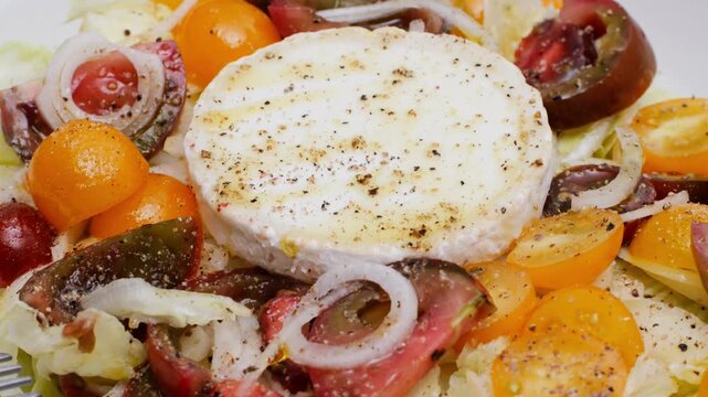 Goat cheese spanish catalonian salad with iceberg vegetables, corn, olives, onion, balsamic sauce close up on plate. Balanced meal with olive oil.