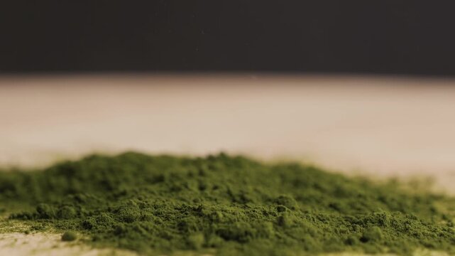 Green chlorella algae powder on a wooden spoon, top view. Healthy nutritional supplement.