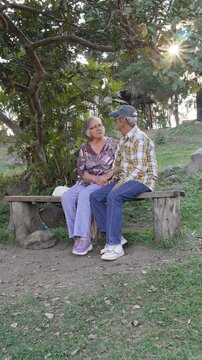Senior Couple Talking on a Rustic Bench in a Natural Park