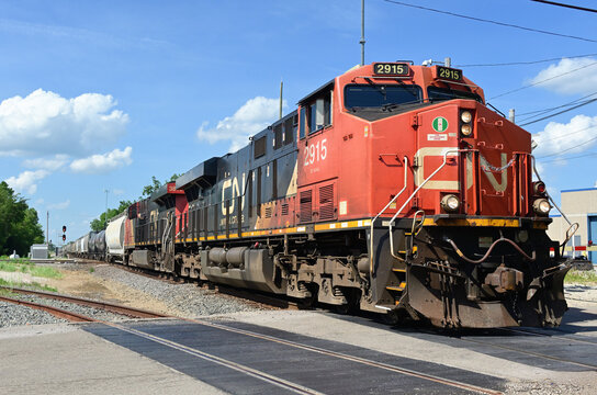 Two locomotives lead a Canadian National Railway freight train through a grade crossing after passing through a diamond crossing in northeastern Illinois.