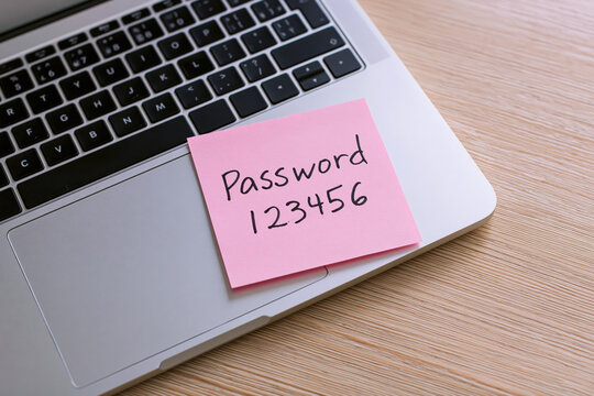 Password written on sticky note on laptop keyboard representing poor digital security and data privacy vulnerability